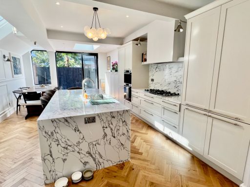Kitchen Extension - Ealing London W13 Modern kitchen with marble island, wooden floor, and large windows.