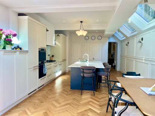 Kitchen extension New kitchen in Ealing with an island, wooden flooring, and ample natural light from skylights.