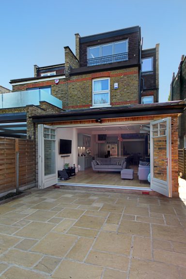 Kitchen extension Clovelly Road Ealing W5 Full house renovation with a spacious patio and large open doors leading to a living area.
