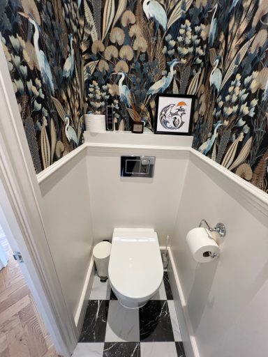 New downstairs toilet Modern bathroom featuring decorative wallpaper, a toilet, and stylish flooring.