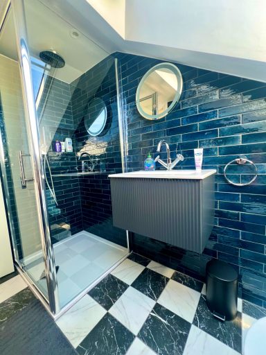 Loft bathroom, Ealing W13 Modern loft bathroom featuring black and blue tiles, round mirrors, and vanity unit. Ealing W13
